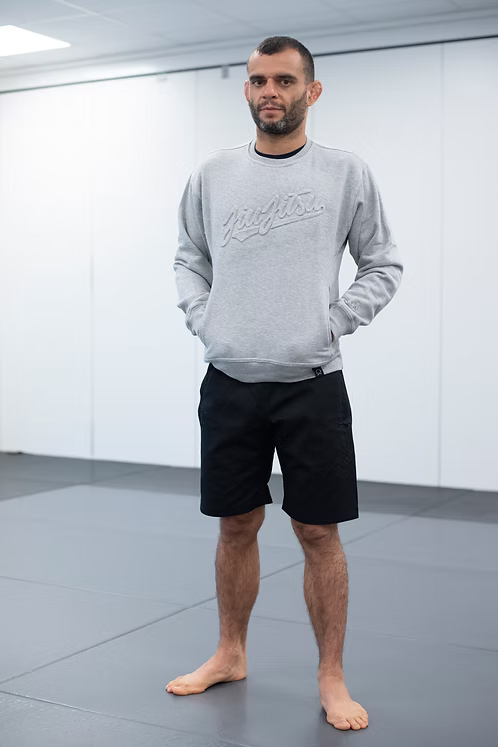 Utøver i svarte Rios Casual Shorts og grå collegegenser på matta