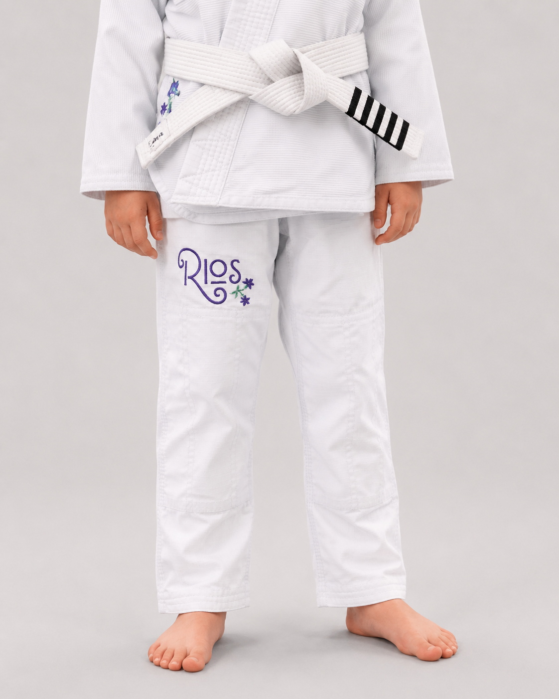 Nærbilde av buksen til Rios Vida Gi for barn med lilla Rios-logo