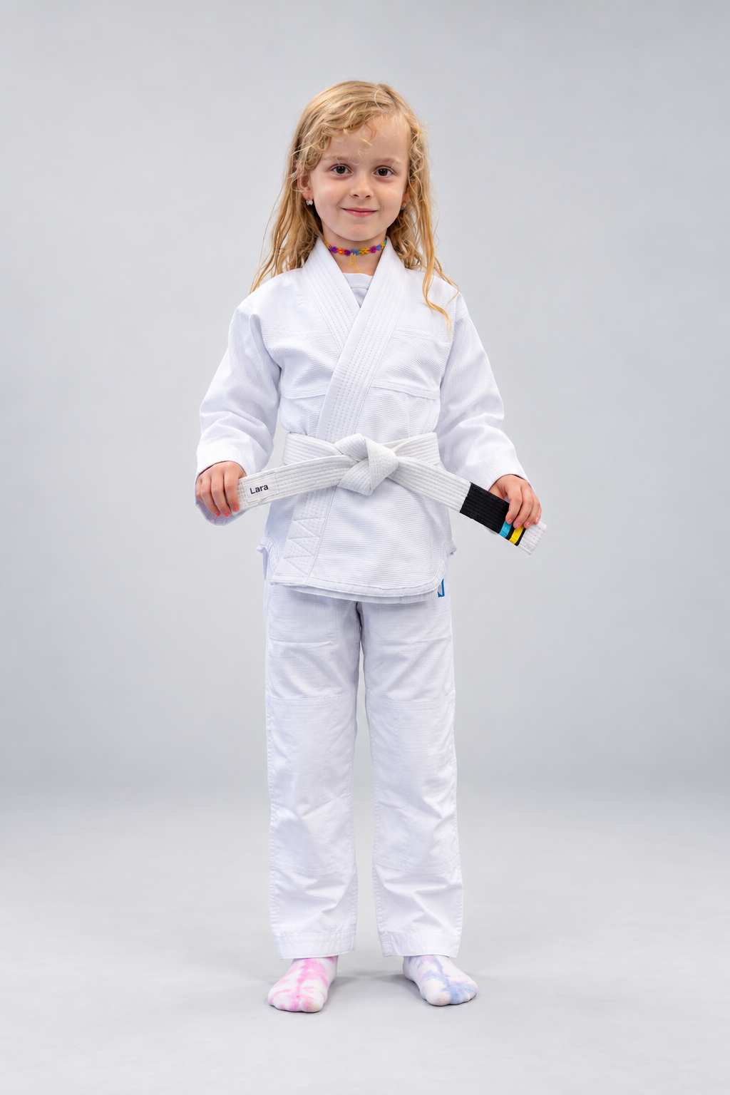 Jente i hvit Rios Kids GI BJJ-drakt med hvitt belte