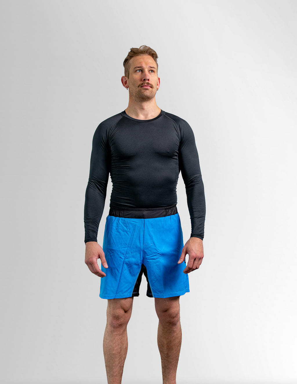 Utøver i blå Rios Athletic Shorts og svart rash guard